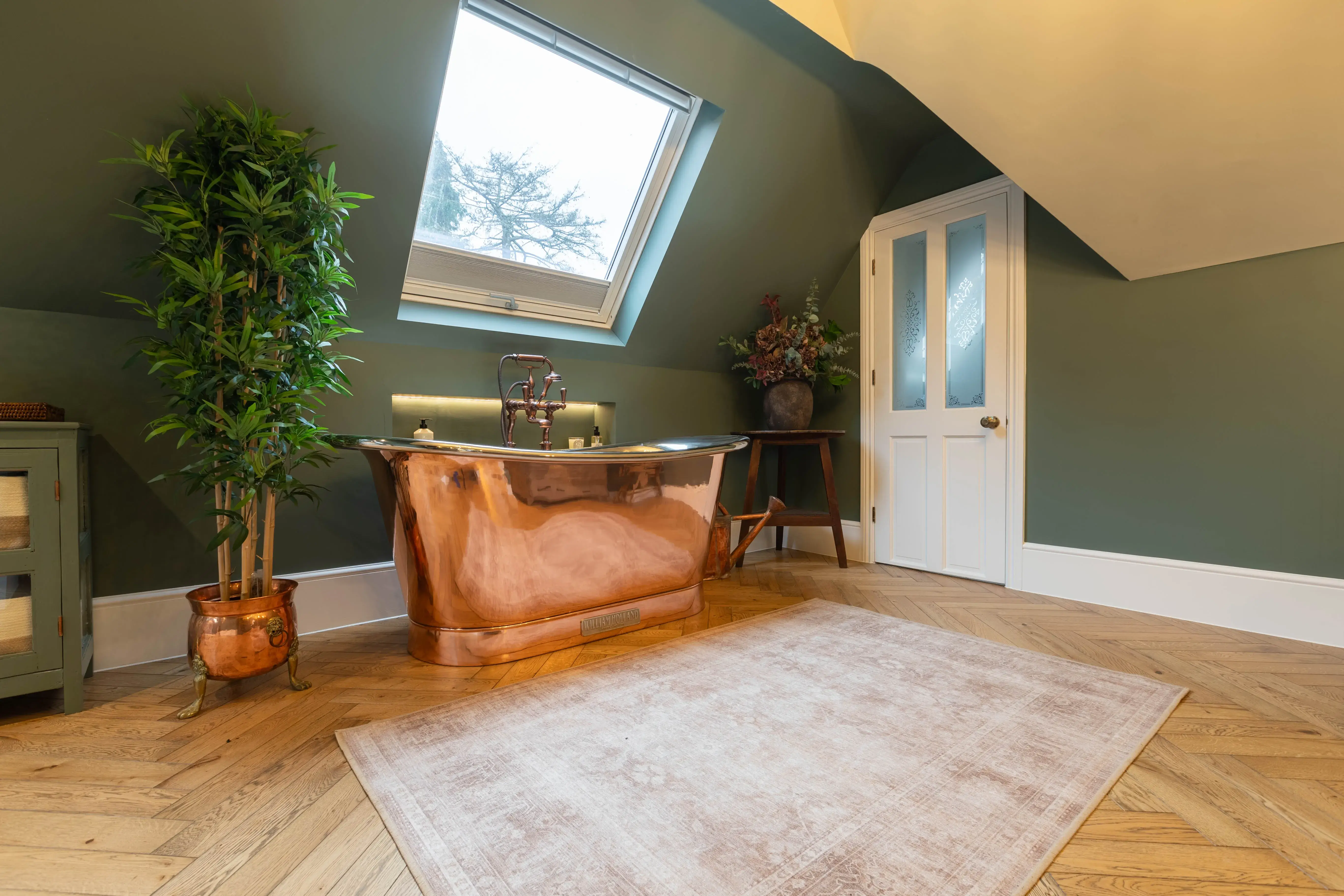 A bathroom with a copper bathtub and a potted plant.