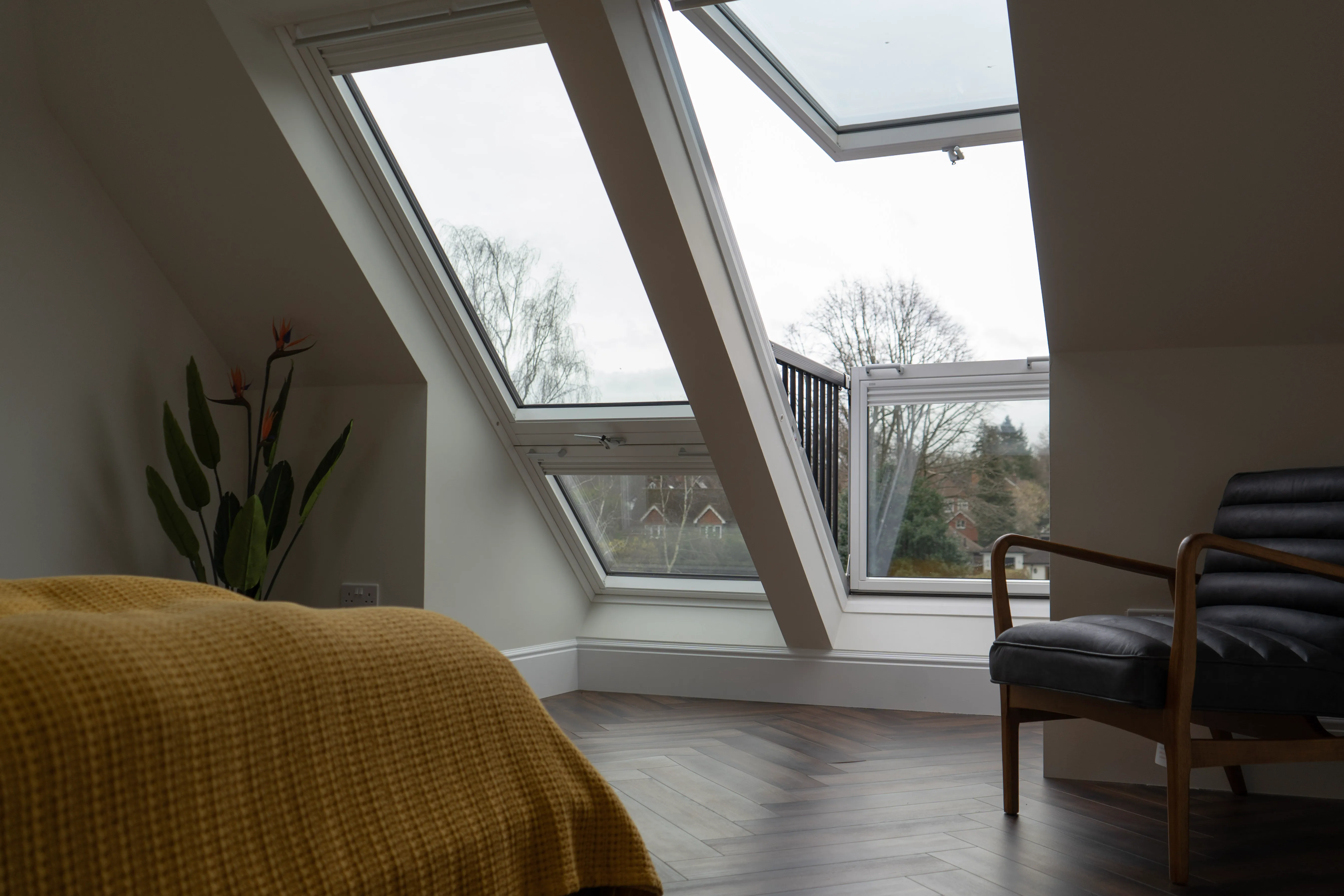 a bedroom with a bed, chair, and two windows