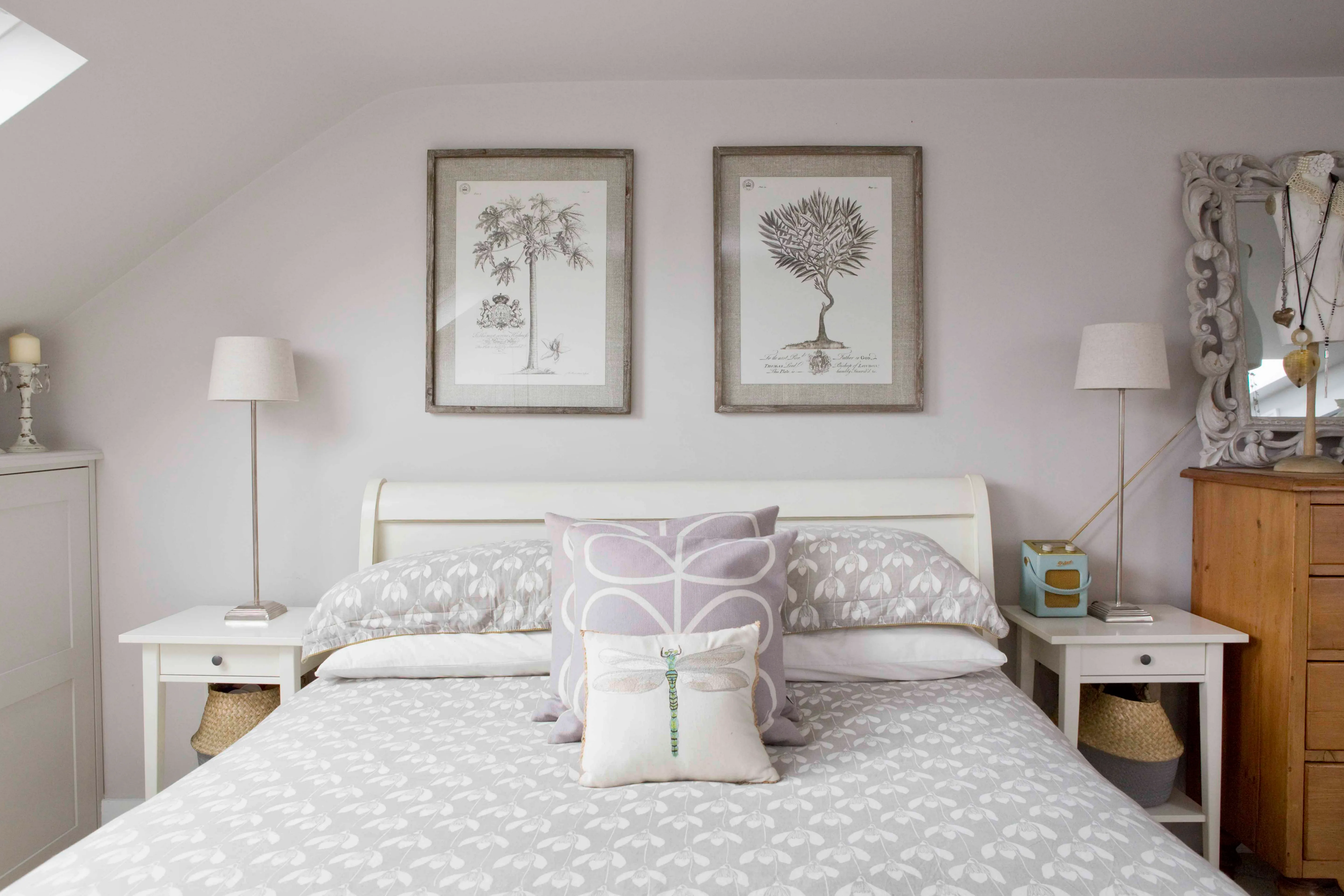 a bedroom with a white bed and two framed pictures on the wall